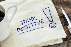 think positive - motivational slogan on a napkin with a cup of c